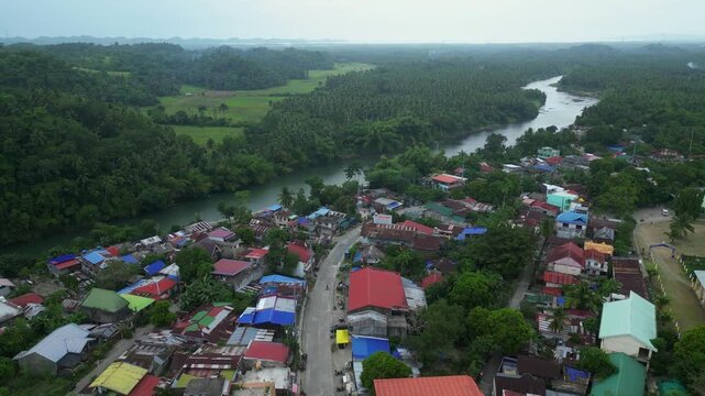Aerial drone footage of Ragay town in Camarines Sur, Philippines, flying from Andaya Park through the town center toward Ragay Bridge, featuring Ragay Municipal Hall, Ragay Cultural Center and surroun