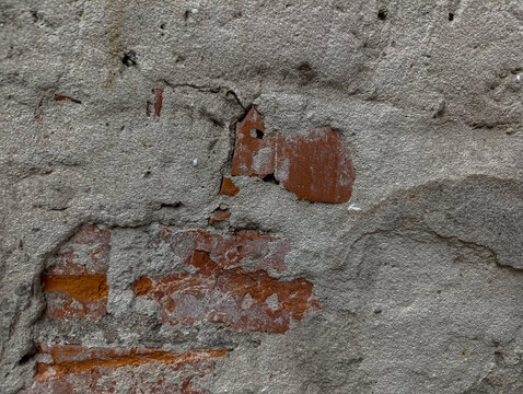 Old cracked plaster wall background with exposed red brick texture.