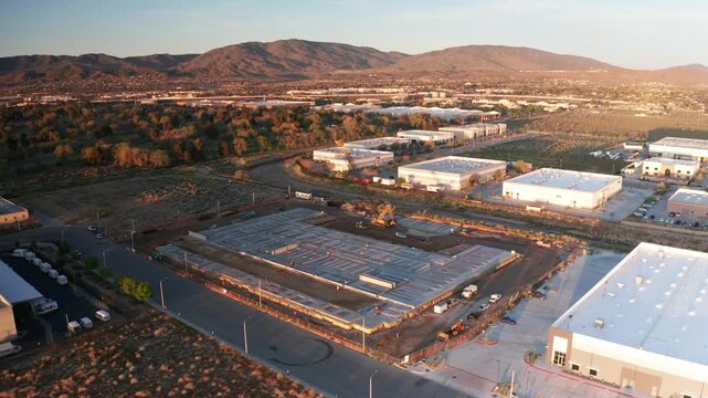 Wide aerial descending shot of an active construction site at daybreak in the Mojave Desert, California. 4K