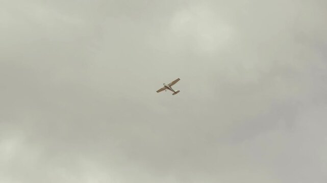 Camera tracks a small airplane flying through an overcast sky