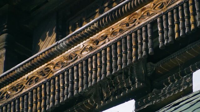 A cinematic slow motion shot through carved pillars revealing the intricate wooden balconies and slate roof of the historic Prashar Rishi pagoda temple in Mandi, Himachal Pradesh.