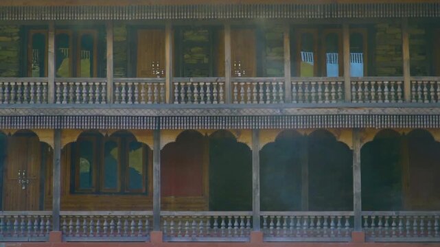 A cinematic slow motion push-in shot through carved pillars revealing the intricate wooden balconies and slate roof of the historic Prashar Rishi pagoda temple in Mandi, Himachal Pradesh.