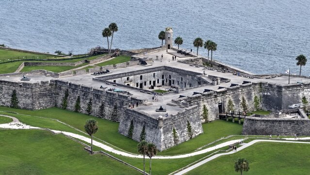 Aerial view of the historic Castillo de San Marcos fort with its stone bastions, grassy moat, and surrounding palm trees along the waterfront in St. Augustine, Florida, United States.