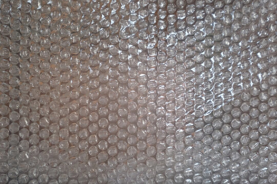 Transparent bubble wrap texture with repeating air pockets, glossy plastic surface, subtle highlights, and realistic packaging material details, ideal for packaging, protection, backgrounds, and 3D vi