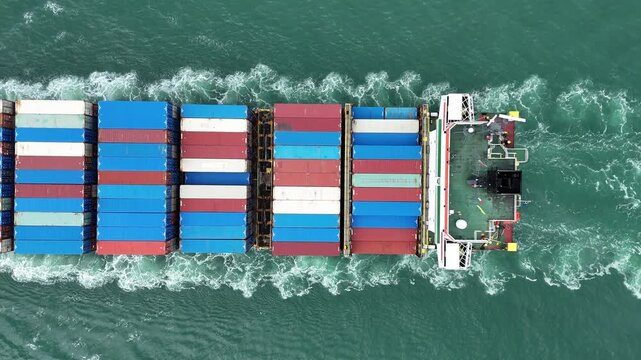Aerial top view of cargo ship with contrail in the ocean sea ship carrying container and running from container international port smart freight shipping by ship service
