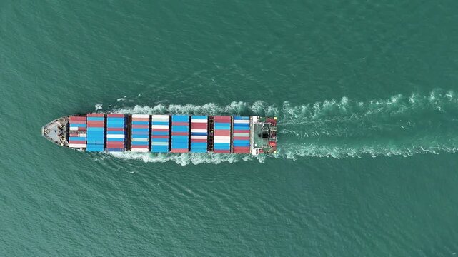 Aerial top view of cargo ship with contrail in the ocean sea ship carrying container and running from container international port smart freight shipping by ship service