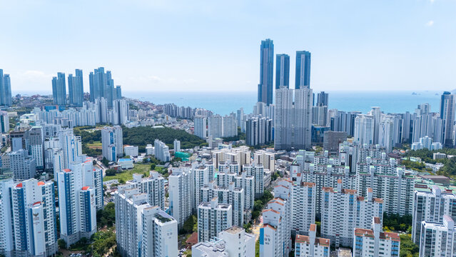 Aerial view of the dense urban landscape of Haeundae-gu with numerous high-rise apartment buildings and skyscrapers overlooking the coastline in Busan, South Korea.