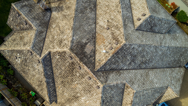 Aerial view of a complex multi-faceted roof with grey slate tiles and chimneys in Lake Oswego, Oregon, United States.