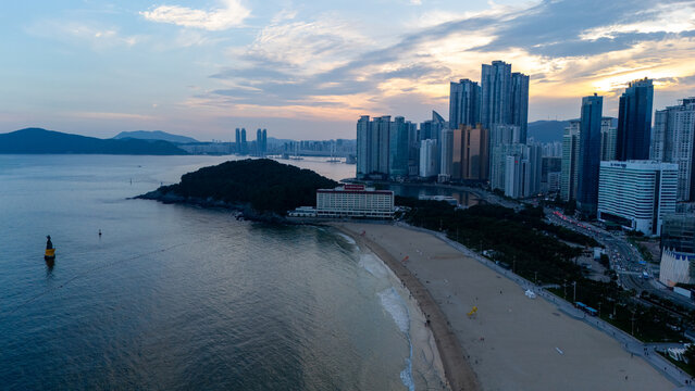 Aerial view of Haeundae Beach with its sandy shoreline, modern skyscrapers, and calm sea waters at sunset in Busan, Busan, South Korea.
