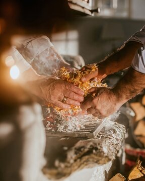Hands of a middle eastern man placing kindling into a wood stove, with warm glowing light and weathered textures for home care and energy brands