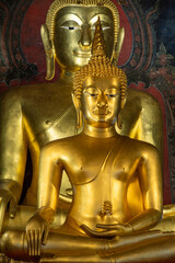Fototapeta premium A close-up view of the sacred golden Phra Phuttha Chinnasi and Phra Suwannakhet Buddha statues inside Wat Bowonniwet Vihara temple.
