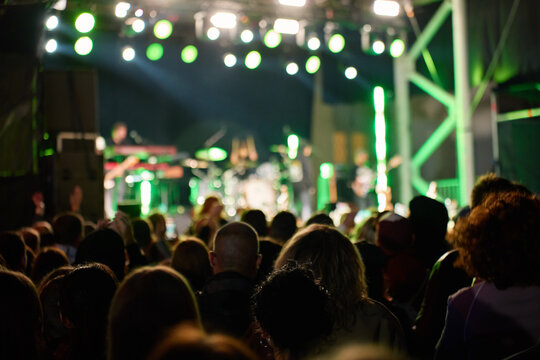 Crowd watching a live concert under bright stage lights at night