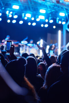 People raising hands and recording a live concert on phones at night