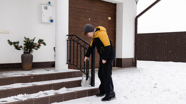 Person shoveling snow from stairs in winter scene outside a house