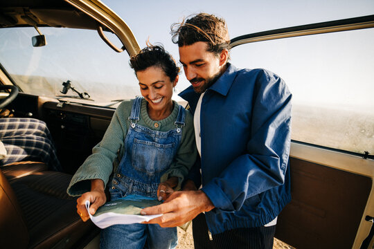 Couple reading a map during a sunny road trip