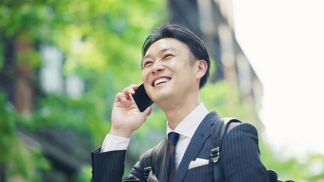 Businessman looking up with a smile during a phone call outdoors