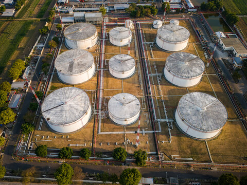 Aerial view of a large industrial fuel storage facility featuring multiple white cylindrical tanks connected by a network of pipes in Boyolali, Central Java, Indonesia.