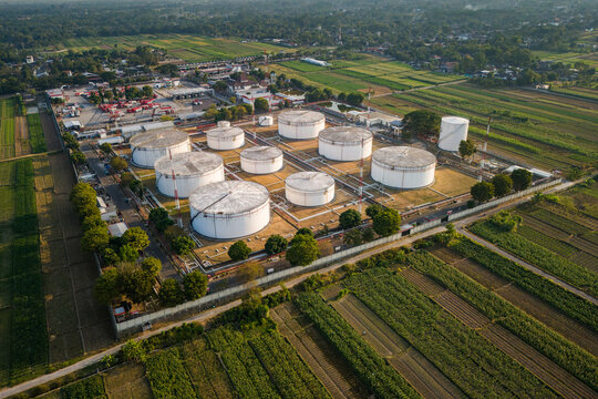 Aerial view of a fuel storage facility with large white cylindrical tanks surrounded by lush agricultural fields and rural landscape in Boyolali, Central Java, Indonesia.