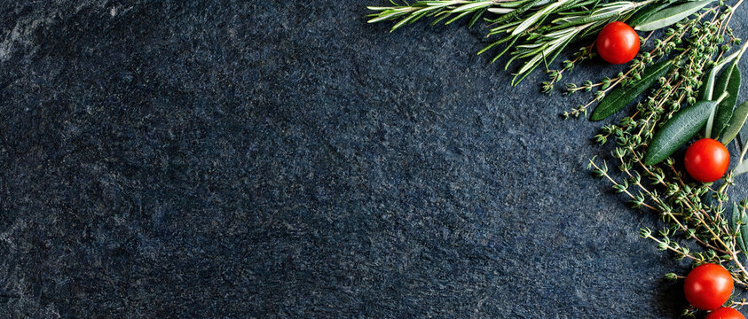 culinary herbs and ripe cherry tomatoes top view flat lay on black slate stone background frame with copy space for italian cooking recipe food menu design horizontal banner banner photography