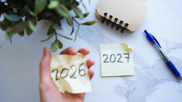 Hand holding 2026 sticky note next to 2027