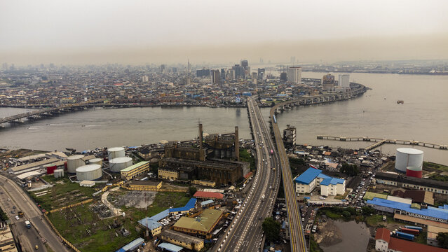 Aerial view of the Eko Bridge and Carter Bridge connecting the mainland to Lagos Island, featuring industrial storage tanks and dense urban development in Lagos, Lagos, Nigeria.