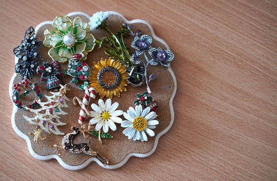 Turkey, August 20, 2025:A vintage collection of sparkling Christmas and floral brooches is displayed on a round cork board. It features enamel pins like a Christmas tree, reindeer, sunflower, daisies