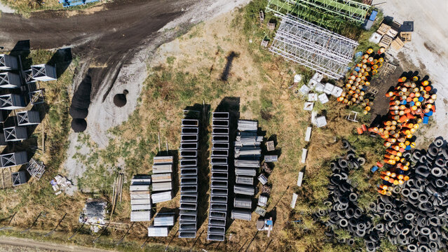 Aerial view of TASYAPI construction site with organized rows of concrete forms, stacks of metal frames, and piles of discarded tires and barrels in Kuzmin, Vojvodina, Serbia.