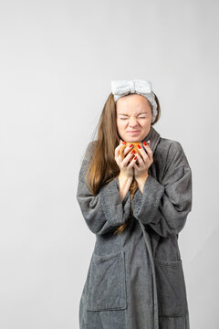 Young woman feeling tired having warm coffee in bathrobe