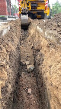Vertical view of deep trench with mini excavator working on street, urban groundwork, road repairs, civil engineering, Industry