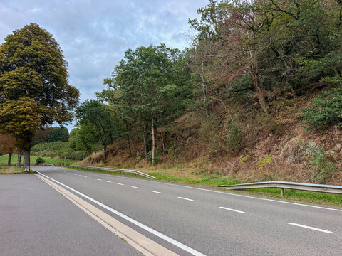 Empty Two-Lane Country Road Through Forested Hills in Reuland, Belgium