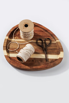 Top view cotton twine spools decorative string and vintage scissors arranged on wooden tray, diy craft workspace and packaging supplies