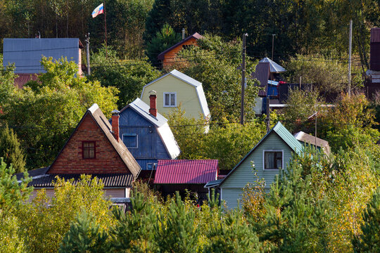 Colorful wooden cottages nestled within a lush green forest, cozy dacha neighborhood with small country houses, Russian countryside summer escape, peaceful woodland residential village view