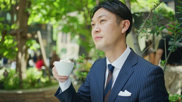 Businessman holding a coffee cup and thinking at an outdoor cafe