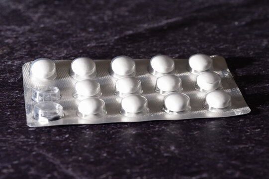 Blisterpackung mit wei&szlig;en Tabletten auf Schiefer