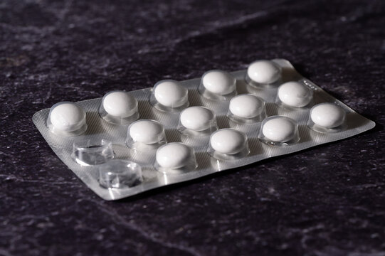 Blisterpackung mit wei&szlig;en Tabletten diagonal auf Schiefer