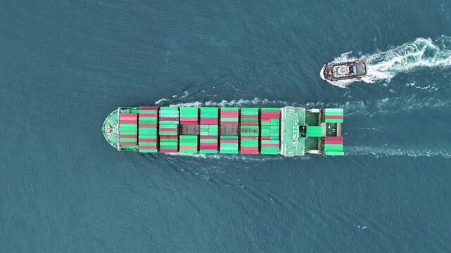 container ship fully loaded with colorful cargo being assisted by a tugboat navigating through the blue ocean. Global maritime logistics and international shipping trade concept