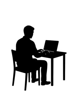 Silhouette of a person working on a laptop at a desk