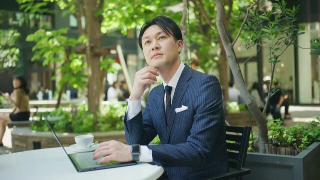 Businessman thinking with a hand on his chin at a cafe terrace