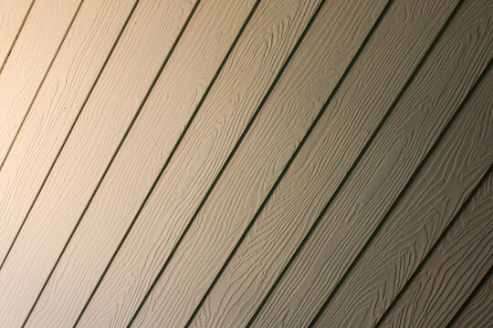 Wooden siding panel with diagonal lines and embossed grain texture, creating neutral architectural background with warm natural detail and repeating pattern for design use