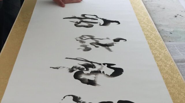 Hands Creating Traditional Chinese Ink Brush Calligraphy on a Scroll