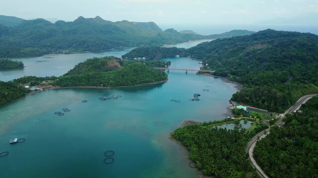 Wide drone perspective over the waters surrounding Cagraray Island, Albay, with Nagtaquin Island visible in the distance and a cloudy tropical sky creating an atmospheric coastal scene.