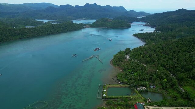 Cloudy aerial view of Cagraray Island in Albay, Philippines, flying over Barangay Bariw toward Sula Bridge and the coastal waters surrounding Nagtaquin Island, with a moody tropical atmosphere.