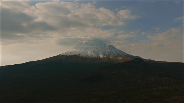 Snow capped Popocatepetl volcano rising above forested slopes in Izta Popo Zoquiapan National Park, Mexico.