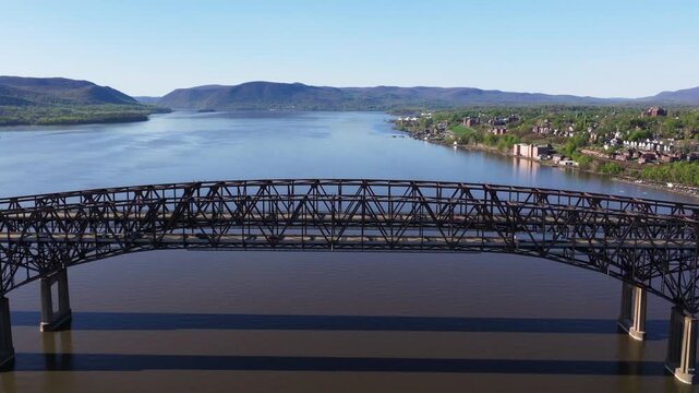 Newburgh-Beacon Bridge spans the Hudson River with mountains and waterfront homes, aerial medium approach