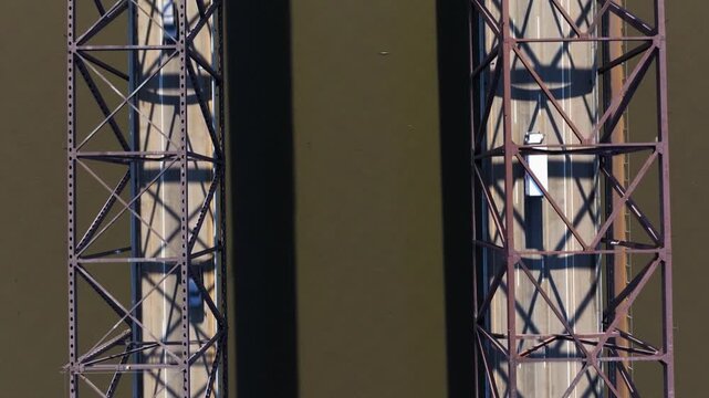 Newburgh-Beacon Bridge decks and steel lattice trusses run parallel over the river, drone tracking forward, top-down textured backdrop
