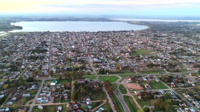 San Miguel del Monte extends around Laguna de Monte, with dense residential blocks, green spaces, roundabouts and regional roads across Buenos Aires Province, Argentina, aerial slide