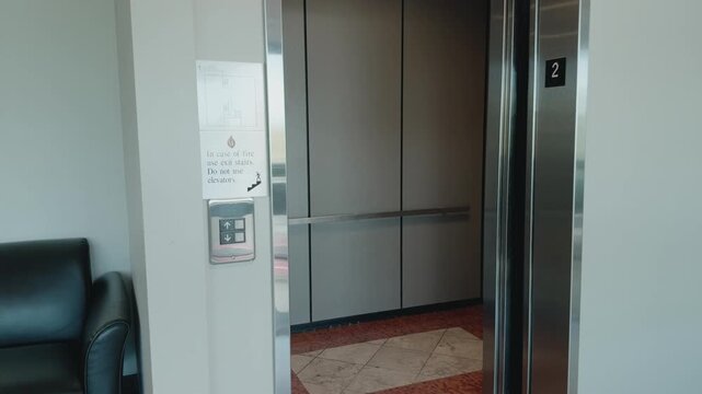 Static view of elevator doors opening, remaining open briefly, then closing again.