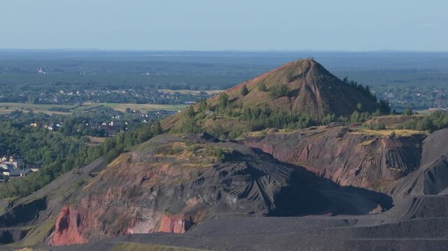 Industrial slag heap rising above a sprawling landscape with a city in the distance