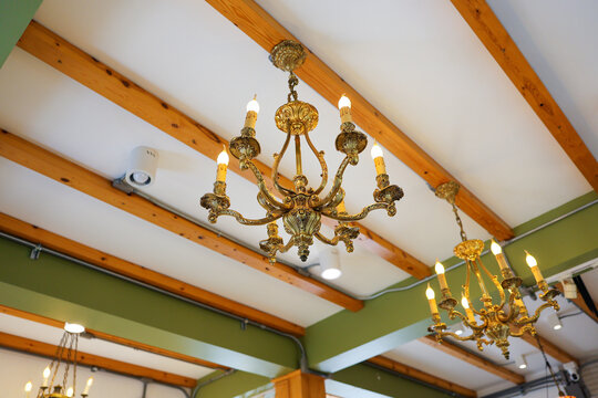 Ornate chandelier hanging from wood beam ceiling in elegant interior with warm lighting and decorative detail