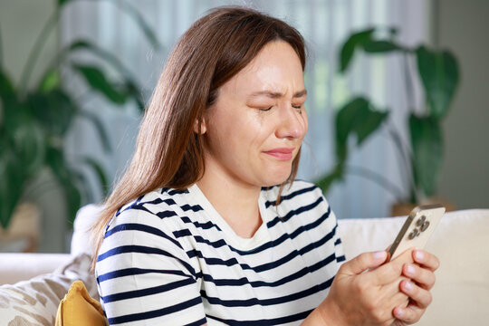 Heartbroken woman crying while looking at smartphone